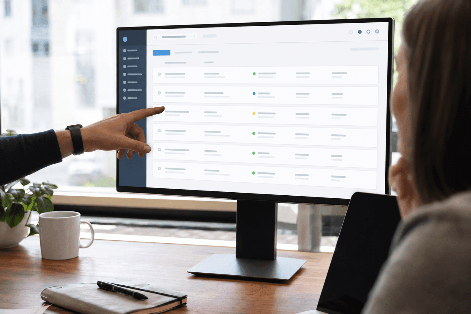 A hand points to a row with a coloured status dot on a large screen showing the working client panel