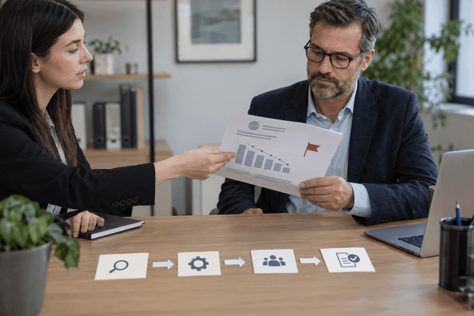 Un analyste remet à un responsable un rapport avec un drapeau d'alerte près d'un graphique.